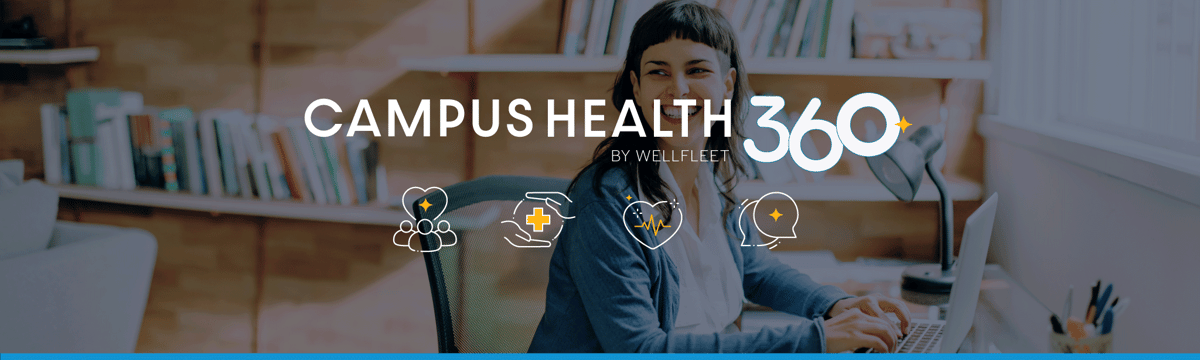 Student smiling at desk and typing on a laptop.